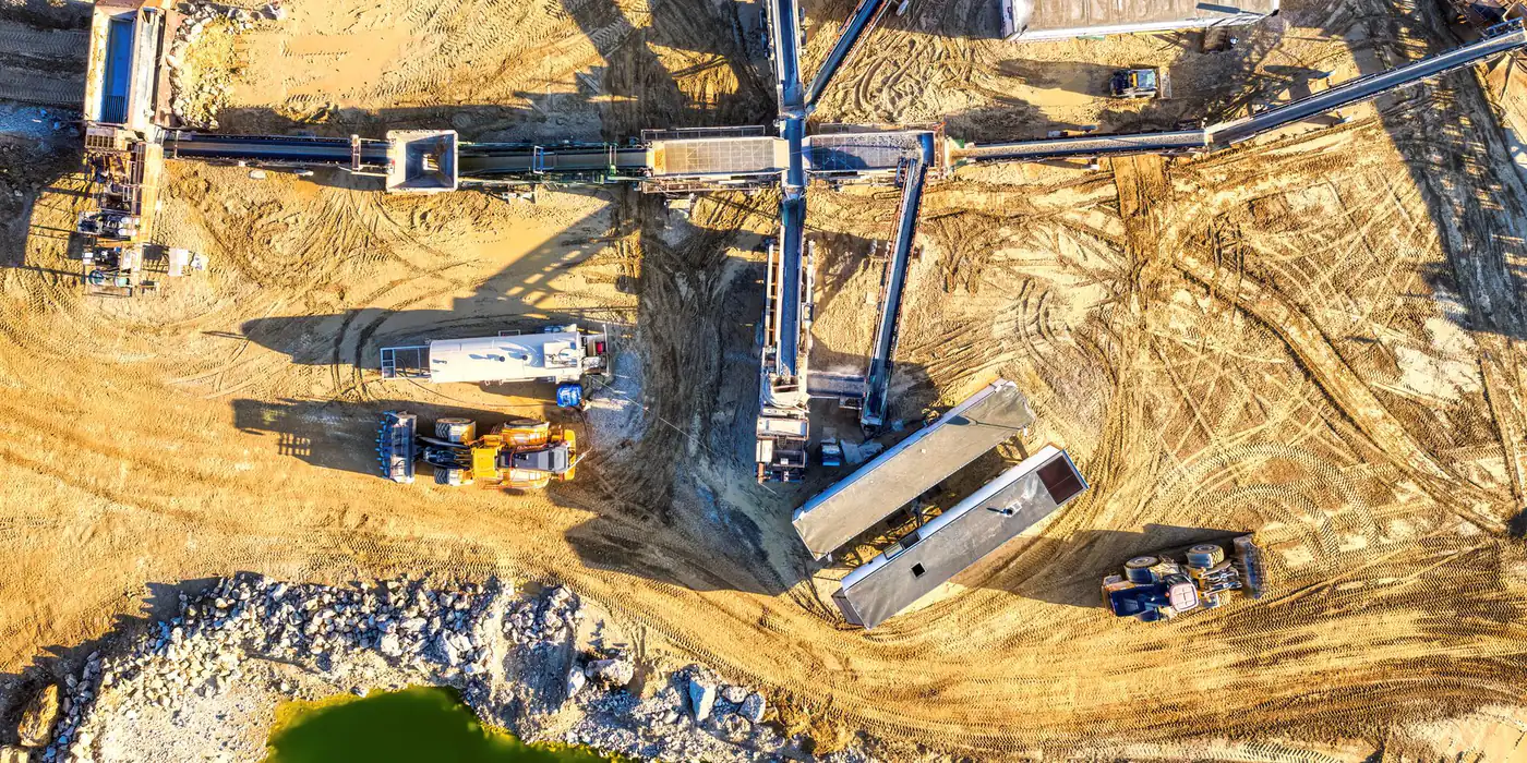 Aerial view of a crushing and screening plant with conveyors radiating across the pad