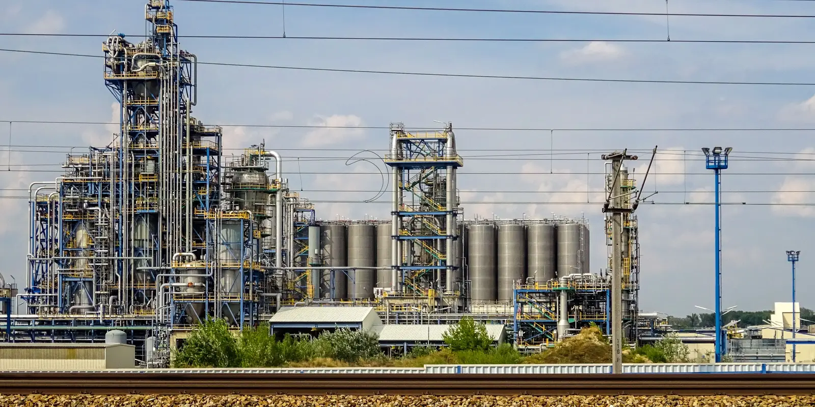 Process plant distillation columns and storage tanks beside a rail line