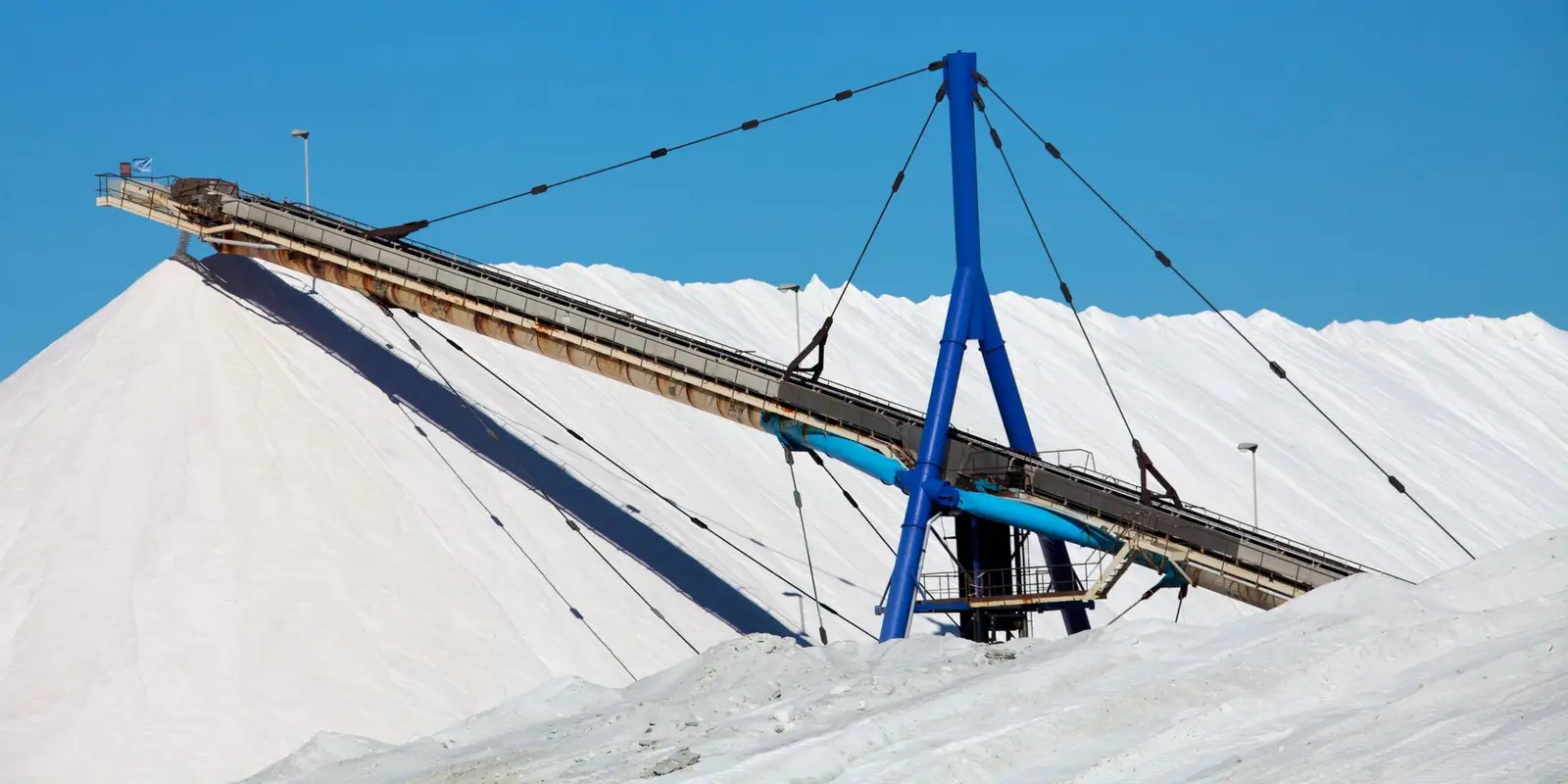 Stacker conveyor discharging onto a stockpile under a clear sky