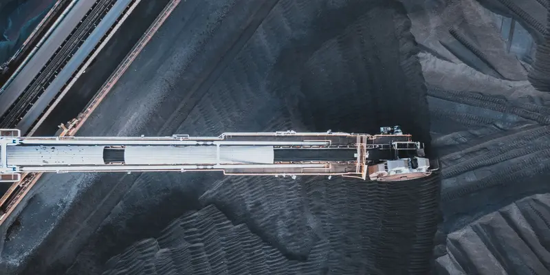 Stacker conveyor over coal stockpiles viewed from directly above