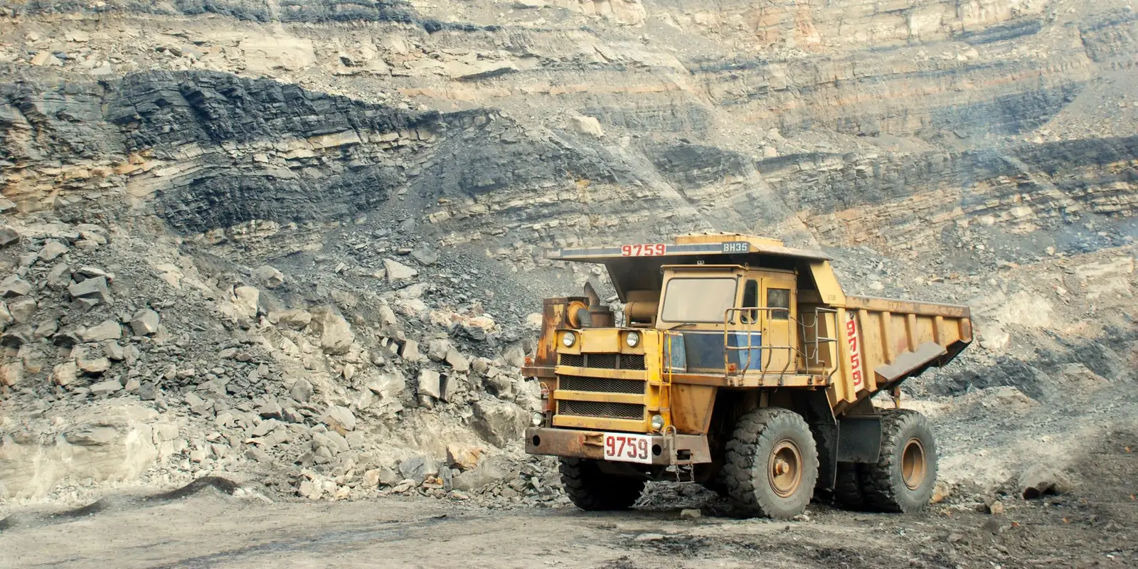 Haul truck working below quarry benches under a clear sky