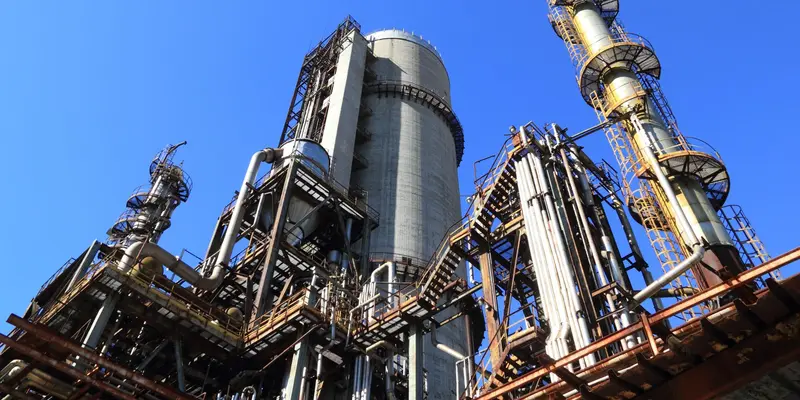 Process plant columns and pipework against a clear blue sky
