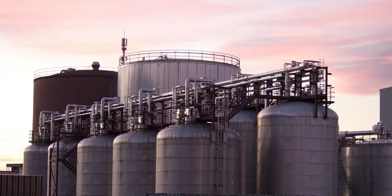 Remote industrial plant with storage tanks and pipework at dusk